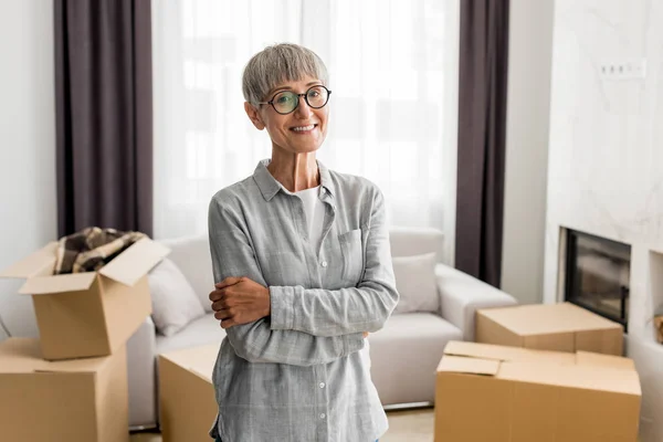 Smiling woman with crossed arms looking at camera in new house — Stock Photo