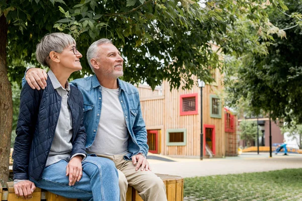 Uomo maturo che abbraccia donna sorridente e distoglie lo sguardo — Foto stock