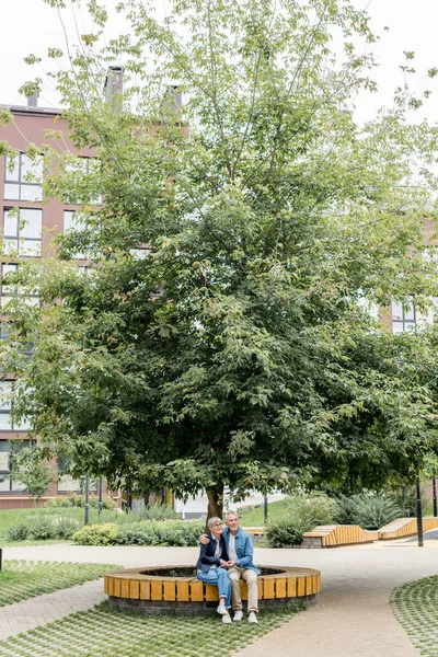 Älterer Mann umarmt lächelnde Frau und schaut nach draußen — Stockfoto