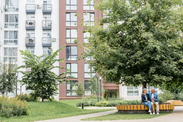 Mature homme étreignant femme souriante et la regardant à l'extérieur — Photo de stock