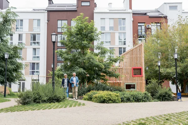 Mature homme et femme marchant près de nouveaux bâtiments à l'extérieur — Photo de stock