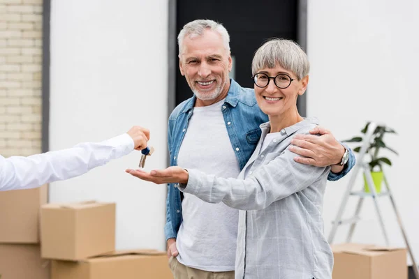 Recortado vista de corredor dando llaves de nueva casa para sonreír hombre y mujer - foto de stock