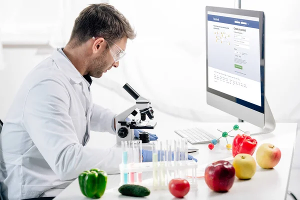 KYIV, UKRAINE - OUTUBRO 4, 2019: visão lateral do nutricionista molecular usando o computador com o site do facebook — Fotografia de Stock