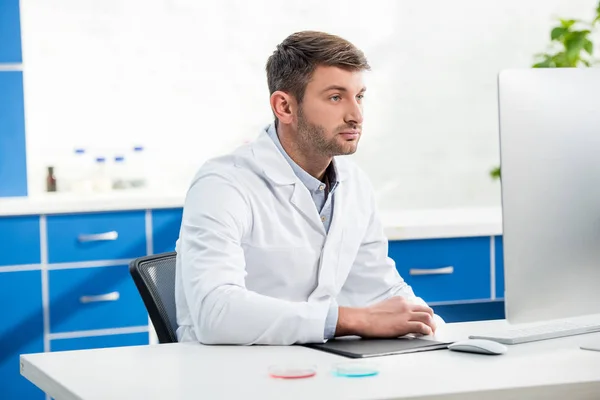 Molecular nutritionist sitting at table and using computer in lab — Stock Photo