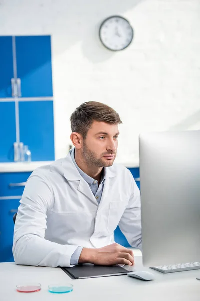 Nutritionniste moléculaire assis à table et utilisant l'ordinateur en laboratoire — Photo de stock