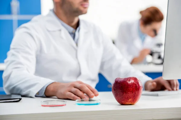 Selective focus of apple and molecular nutritionists on background — Stock Photo