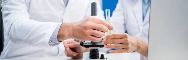Panoramic shot of molecular nutritionists holding test tube in lab — Stock Photo