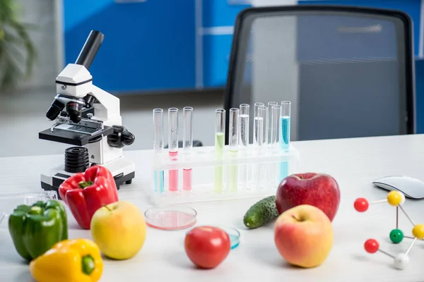 Microscope, fruit, vegetables, test tubes on table in lab — Stock Photo