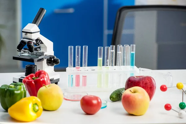 Microscópio, frutas, legumes, tubos de ensaio na mesa em laboratório — Fotografia de Stock