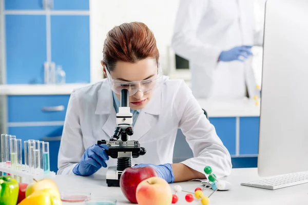 Selective focus of molecular nutritionists using microscope in lab — Stock Photo