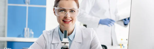Panoramic shot of smiling molecular nutritionist looking at camera — Stock Photo