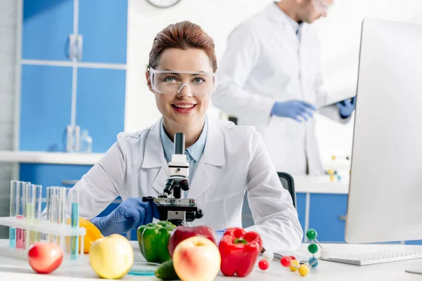 Selective focus of smiling molecular nutritionist looking at camera — Stock Photo