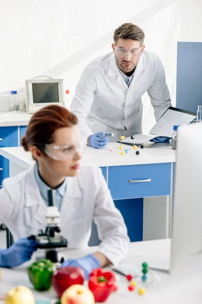 Selective focus of molecular nutritionist looking at colleague in lab — Stock Photo
