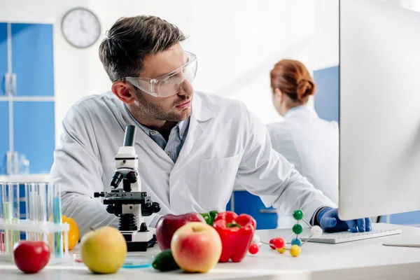 Molecular nutritionist in white coat using computer in lab — Stock Photo