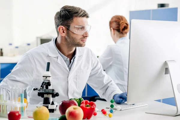 Molecular nutritionist in white coat using computer in lab — Stock Photo