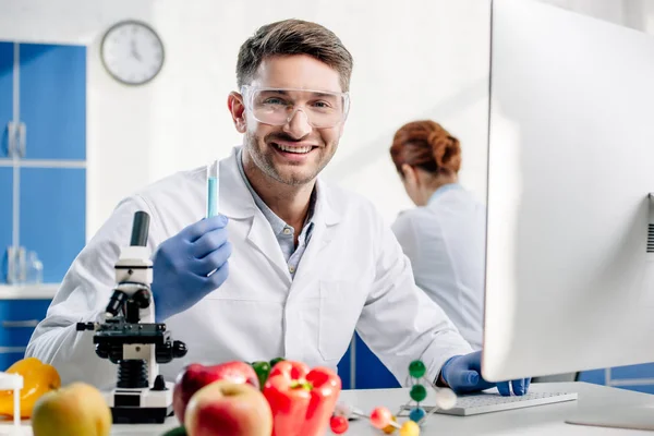 Selective focus of smiling molecular nutritionist holding test tube — Stock Photo