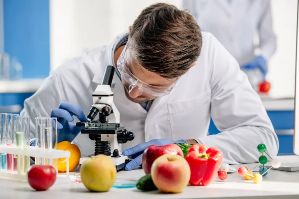 Nutritionniste moléculaire en pelage blanc au microscope en laboratoire — Photo de stock