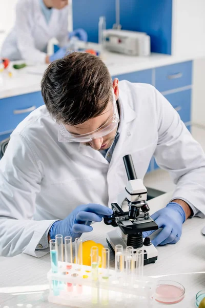 Molecular nutritionist in white coat using microscope in lab — Stock Photo