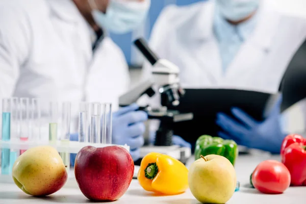 Enfoque selectivo de manzanas, pimientos y tomate en laboratorio - foto de stock