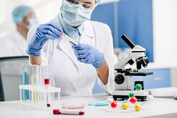 Обрезанный взгляд генетического консультанта в белом халате, делающего тест ДНК в лаборатории — стоковое фото