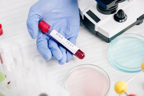 Cropped view of genetic consultant holding test tube with dna test lettering — Stock Photo