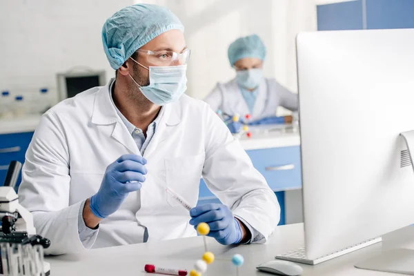Enfoque selectivo de consultor genético haciendo la prueba de ADN y mirando a la computadora en el laboratorio - foto de stock