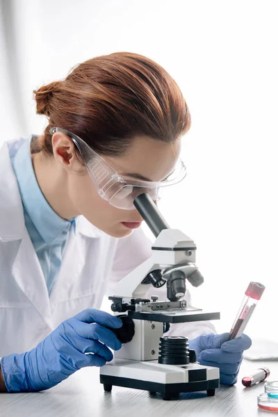 Генетический консультант в белом халате с помощью микроскопа в лаборатории — стоковое фото