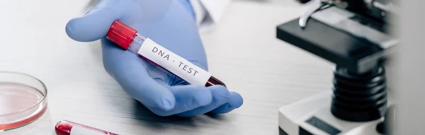 Plano panorámico del consultor genético que sostiene el tubo de ensayo con la prueba del ADN - foto de stock