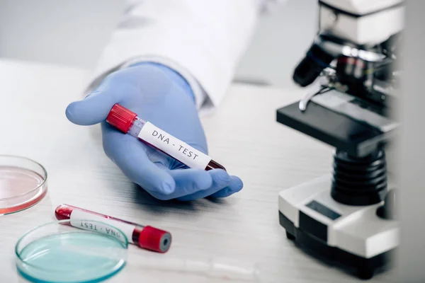 Cropped view of genetic consultant holding test tube with dna test — Stock Photo