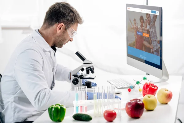 KYIV, UKRAINE - OCTOBER 4, 2019: side view of molecular nutritionist using computer with couchsurfing website — Stock Photo