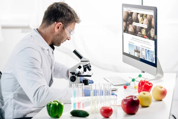 KYIV, UKRAINE - OCTOBER 4, 2019: side view of molecular nutritionist using computer with depositphotos website — Stock Photo