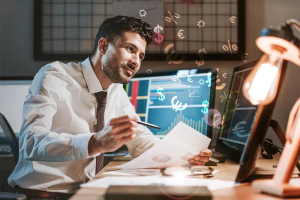 Glücklicher Händler mit Papier in der Nähe von Computern mit Grafiken, Dollar- und Euro-Zeichen — Stockfoto