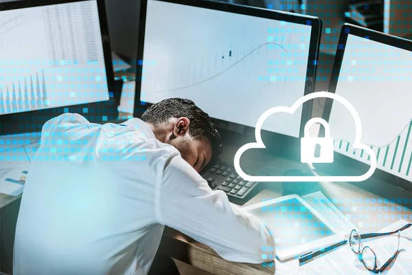 Müder bi-rassischer Händler schläft in der Nähe von Computern mit Grafiken und Wolke mit Vorhängeschloss — Stockfoto