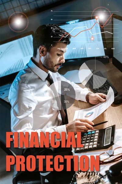 Bi-racial trader using calculator and holding charts and graphs near financial protection letters — Stock Photo