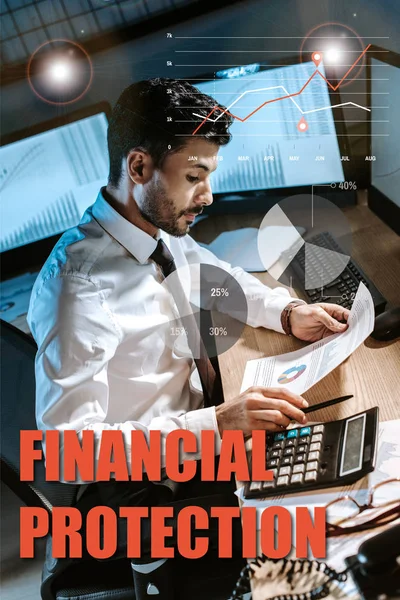 Comerciante bi-racial utilizando calculadora y la celebración de gráficos y gráficos cerca de cartas de protección financiera — Stock Photo