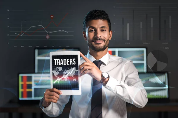 Happy bi-racial man holding digital tablet with traders letters — Stock Photo