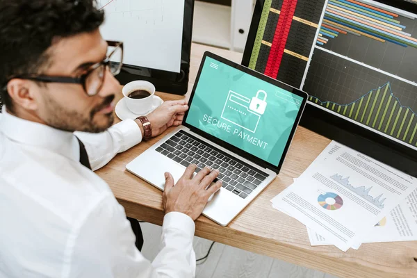 Selective focus of bi-racial trader using laptop with secure payment letters — Stock Photo