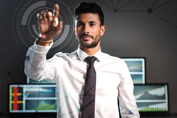 Selective focus of handsome bi-racial trader pointing with finger near computers on background — Stock Photo