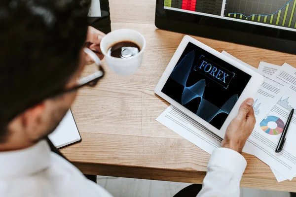 Selective focus of trader holding cup and digital tablet with forex letters — Stock Photo