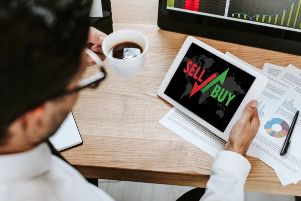 Selective focus of trader holding cup and digital tablet with sell and buy letters — Stock Photo