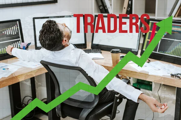 Bi-racial man with outstretched hands sitting near computers and traders letters — Stock Photo