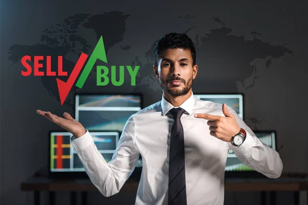 Bi-racial trader pointing with finger at sell and buy letters — Stock Photo