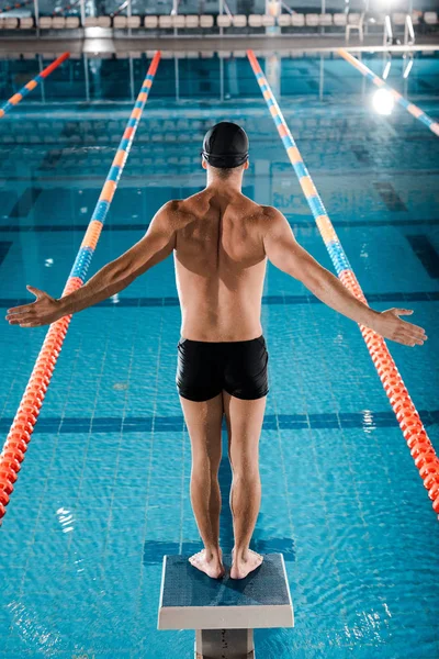 Rückenansicht von Schwimmerin, die mit ausgestreckten Händen in Schwimmbadnähe steht — Stockfoto