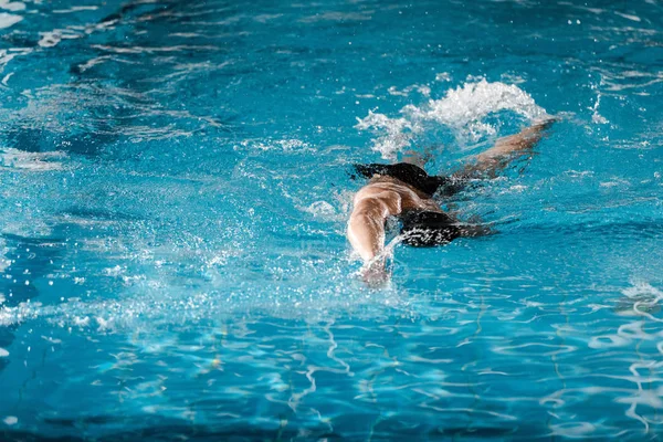 Atlético homem mergulho na piscina com água azul — Fotografia de Stock