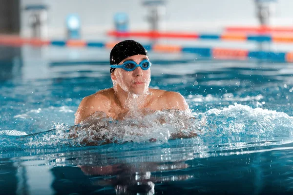Foco seletivo de homem atlético bonito em óculos e touca de natação na piscina — Fotografia de Stock