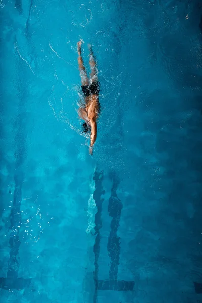 Vista superior del deportista nadando delante gatear en agua azul - foto de stock