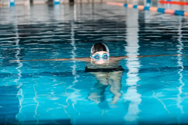 Vista recortada de nadador en gorra de natación y googles en agua - foto de stock