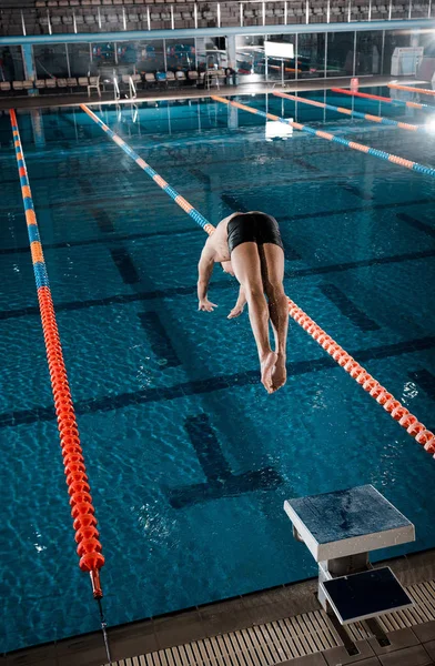 Desportista mergulho na água na piscina — Fotografia de Stock