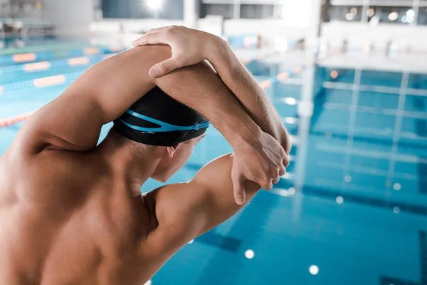 Visão traseira do homem na touca de natação que estica perto da piscina — Fotografia de Stock