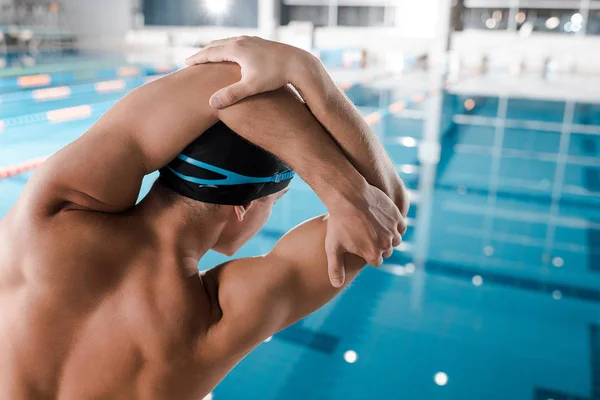 Vue arrière de l'homme en bonnet de bain s'étendant près de la piscine — Photo de stock